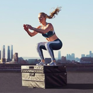  Woman with ponytail doing squats on a city rooftop with skyline in the background 